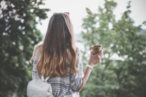 長い髪の女性が紙コップを持っている